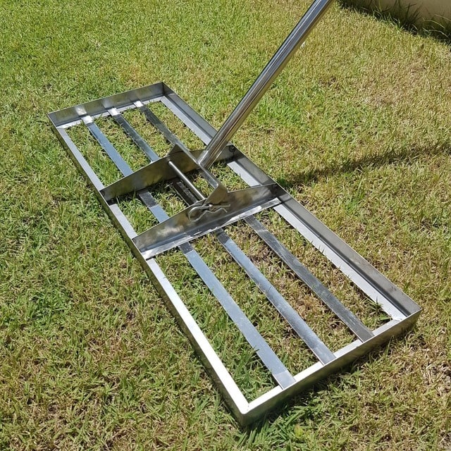 Stainless steel lawn lute head resting on a lawn, with its locking pin and handle